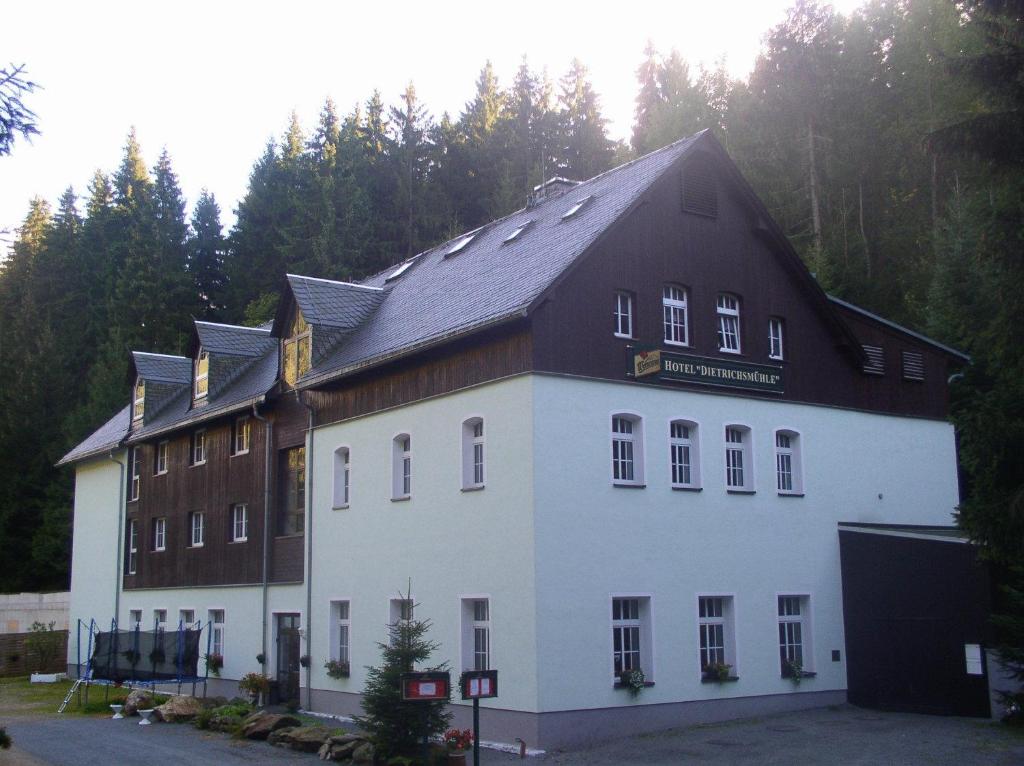a large white building with a black roof at Waldhotel Dietrichsmühle in Crottendorf