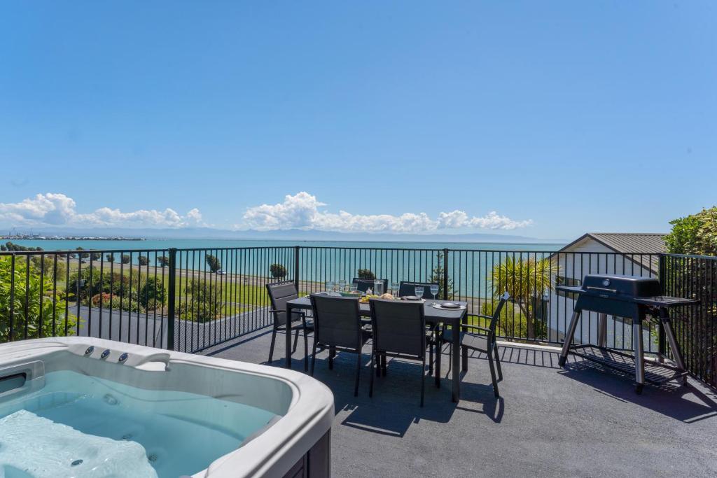 uma banheira de hidromassagem numa varanda com uma mesa e cadeiras em Ocean Spa Views em Nelson
