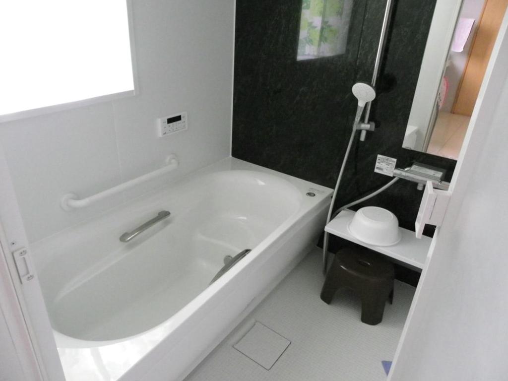 a white bathroom with a tub and a sink at Guest House Miyakojima in Miyako-jima