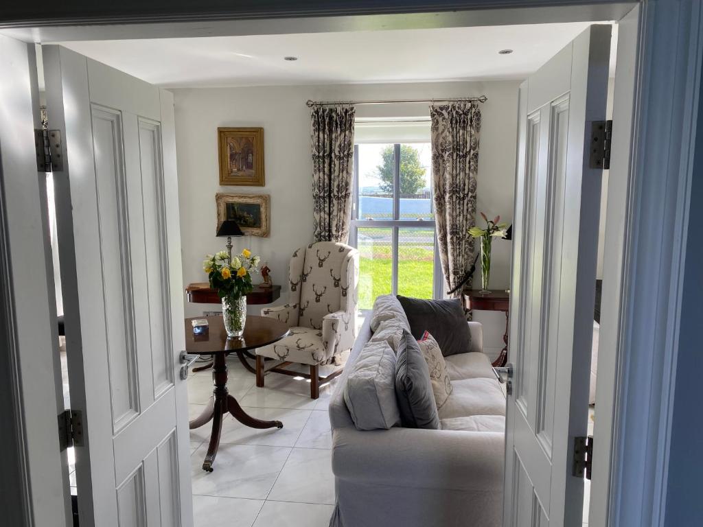 a living room with a couch and a table and a window at Farmhouse Boutique in Ballyheigue