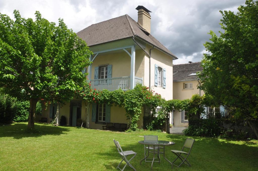 ein Haus mit einem Tisch und Stühlen im Hof in der Unterkunft Gîte d'étape Le Couvent d'Ossau in Louvie Juzon