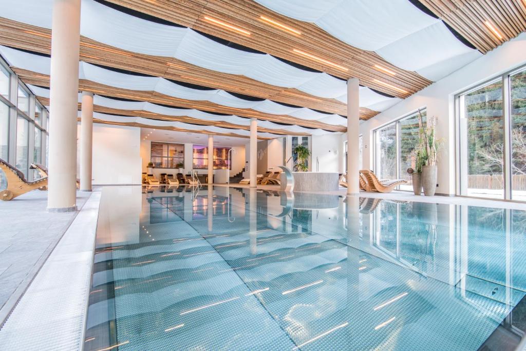 an indoor swimming pool with glass floors and windows at Sporthotel Zoll in Vipiteno