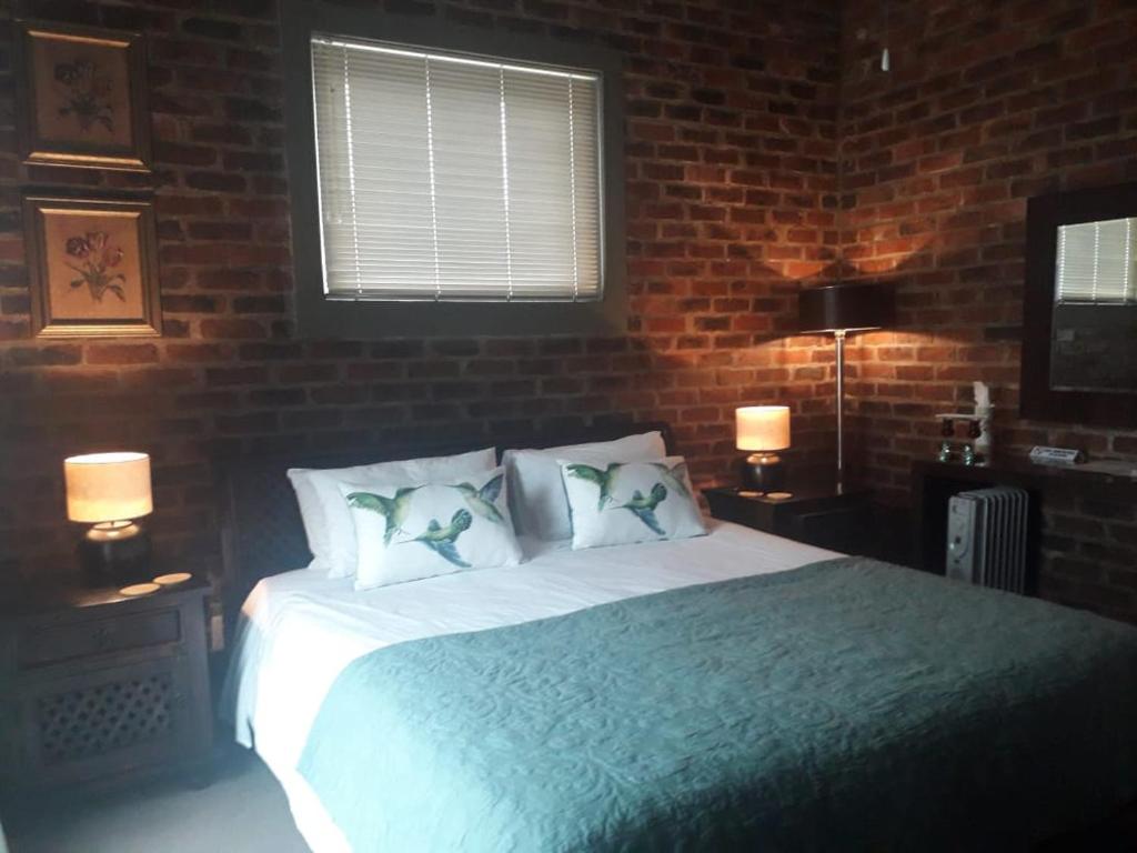 a bedroom with a large bed with a brick wall at 712@Rest in Dullstroom