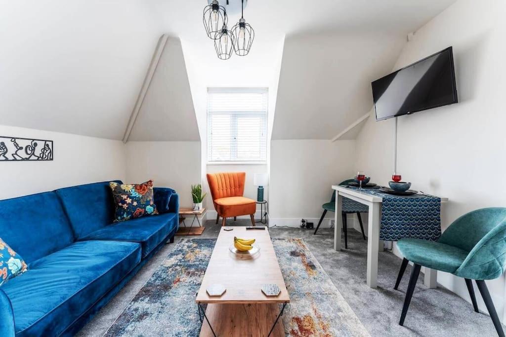 uma sala de estar com um sofá azul e uma mesa em The Coastal Loft em Bournemouth