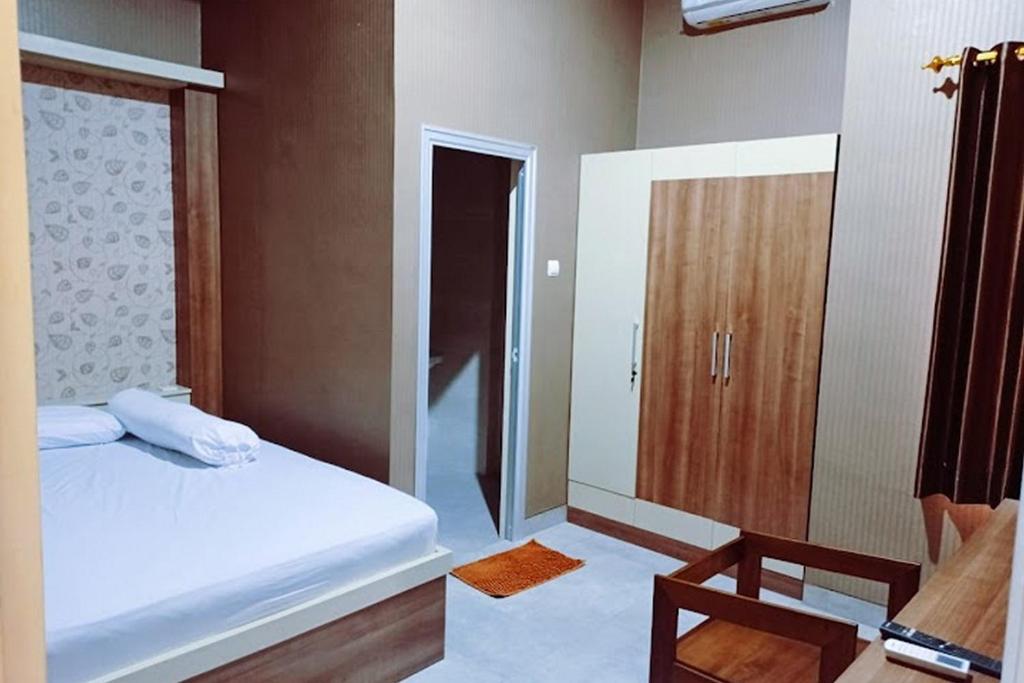 a bedroom with a bed and a wooden cabinet at RedDoorz near Simpang Tujuh Kudus in Kudus