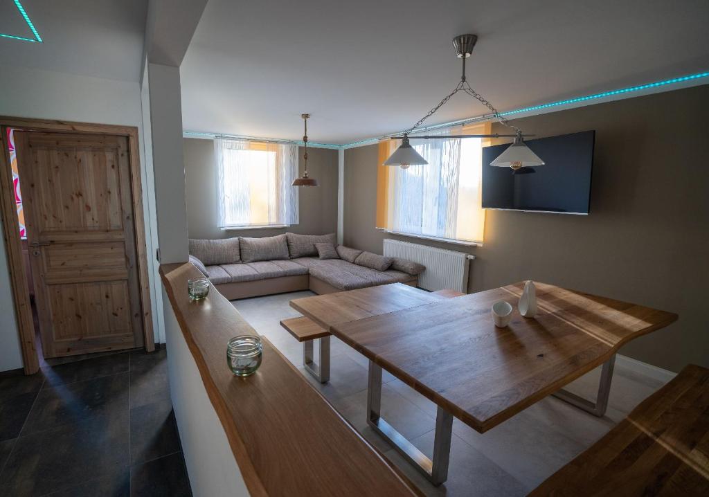a living room with a wooden table and a couch at Ferienhaus Thüringer Wald - Garten & Terrasse in Bischofrod