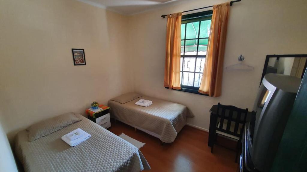 a small room with two beds and a window at Pousada Sayonara in Atibaia