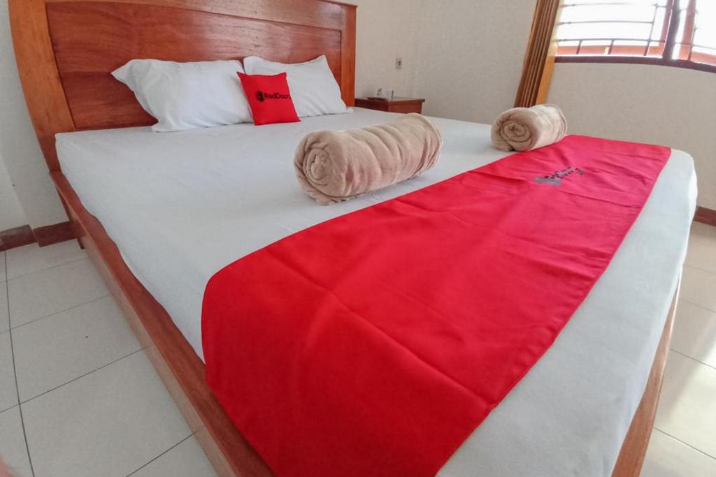 a bedroom with a bed with a red blanket on it at RedDoorz Syariah at Abemoch Kampkey in Tobadi