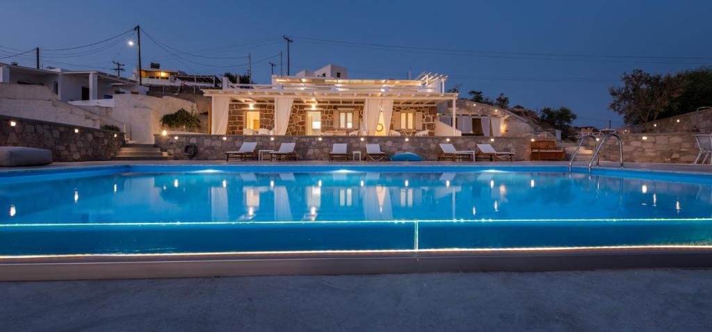 a swimming pool at night with a house in the background at Anemi Suites in Adamas