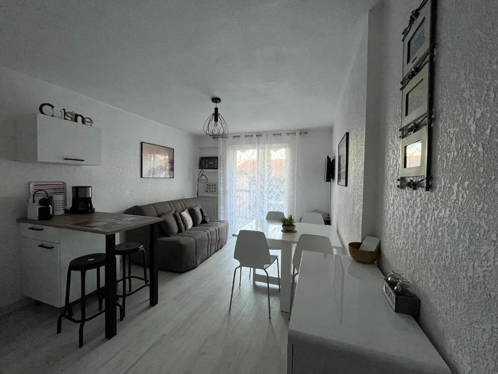 ein Wohnzimmer und eine Küche mit einem Sofa und einem Tisch in der Unterkunft Appartement Les Pieds dans l'eau in Collioure