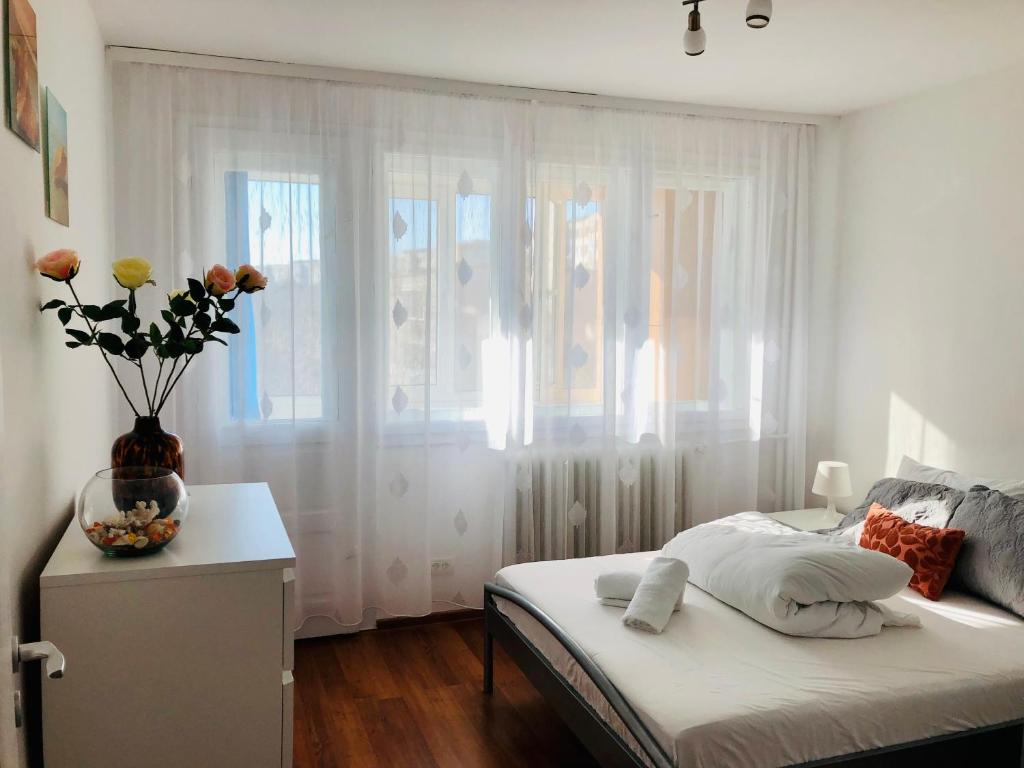a bedroom with a bed with a vase of flowers on a table at LOVELY apartment near Iulius TOWN - Biggest Shoping Center IP19 in Timişoara