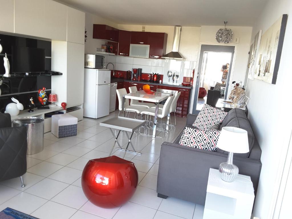 a living room and kitchen with a couch and a table at Les sables d’or in Saint-Jean-de-Monts