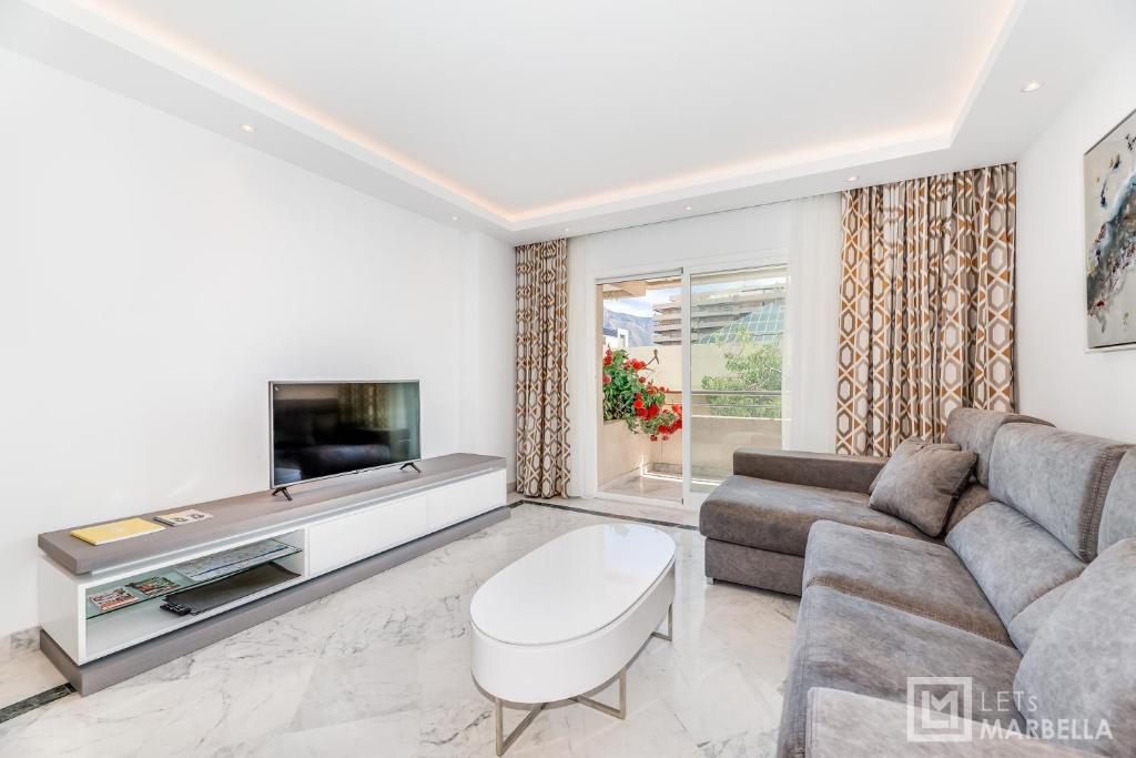 a living room with a couch and a tv at LetsMarbella - NEW 2BR APARTMENT IN PUERTO BANUS - POOL & PARKING in Marbella