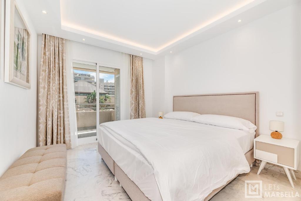 biała sypialnia z dużym łóżkiem i oknem w obiekcie LetsMarbella - NEW 2BR APARTMENT IN PUERTO BANUS - POOL & PARKING w Marbelli