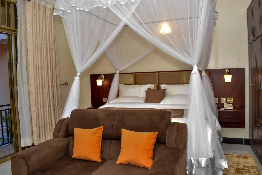 - une chambre avec un lit et un canapé avec des oreillers orange dans l'établissement Studio - Sleeps 2 - Free Shuttle, à Entebbe