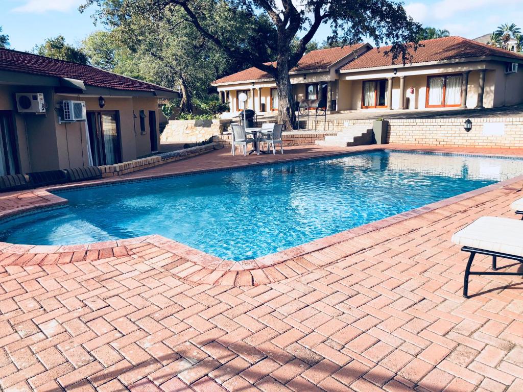 a swimming pool in a yard with a brick patio at Vahlavi Lodge in Giyani