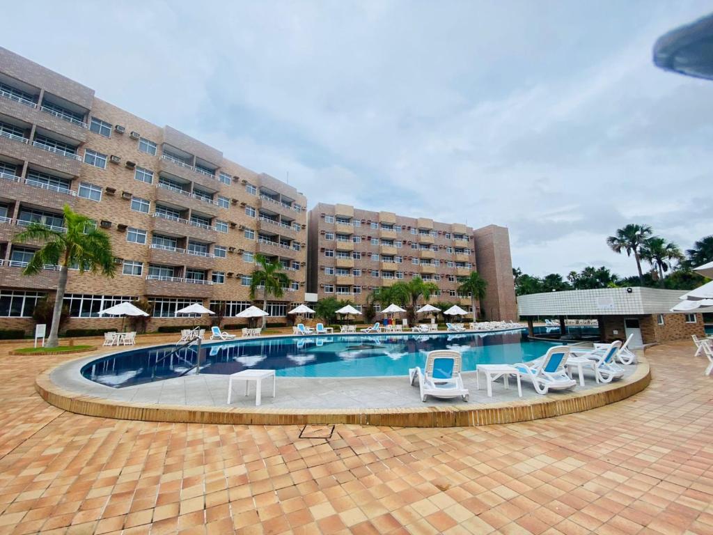uma piscina com cadeiras e guarda-sóis ao lado de um hotel em Gran lençóis flat Residence em Barreirinhas