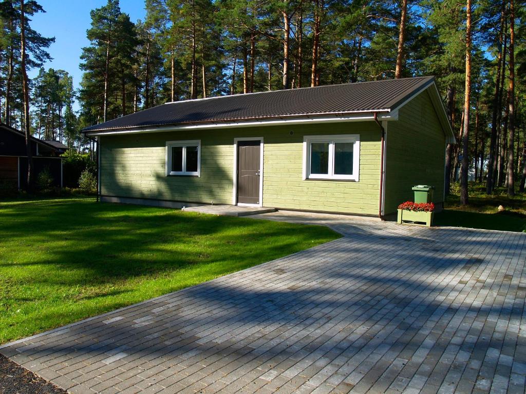 une petite maison verte avec une allée. dans l'établissement Norges puhkemaja, à Papsaare