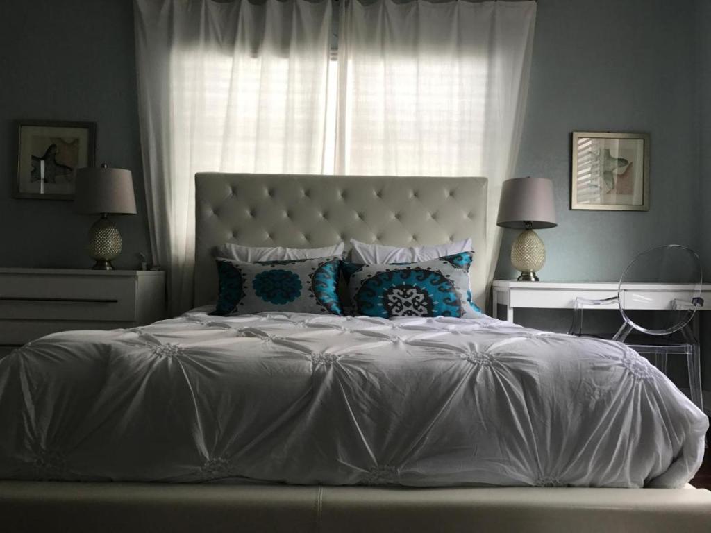 una camera da letto con un letto bianco con cuscini e una finestra di Sun Sand and Love - Lovely 2 Beds, 2 Bath Condo a Miami Beach