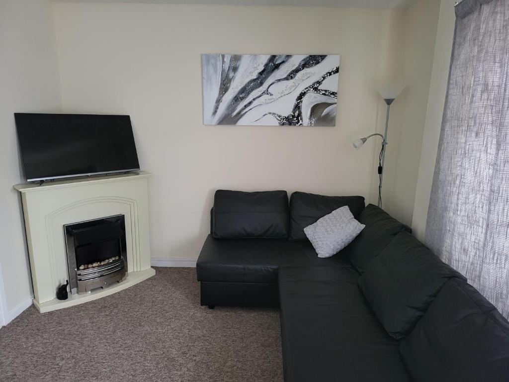 ein Wohnzimmer mit einem schwarzen Sofa und einem Kamin in der Unterkunft Sandy Beach Hill View Apartment Brean in Brean