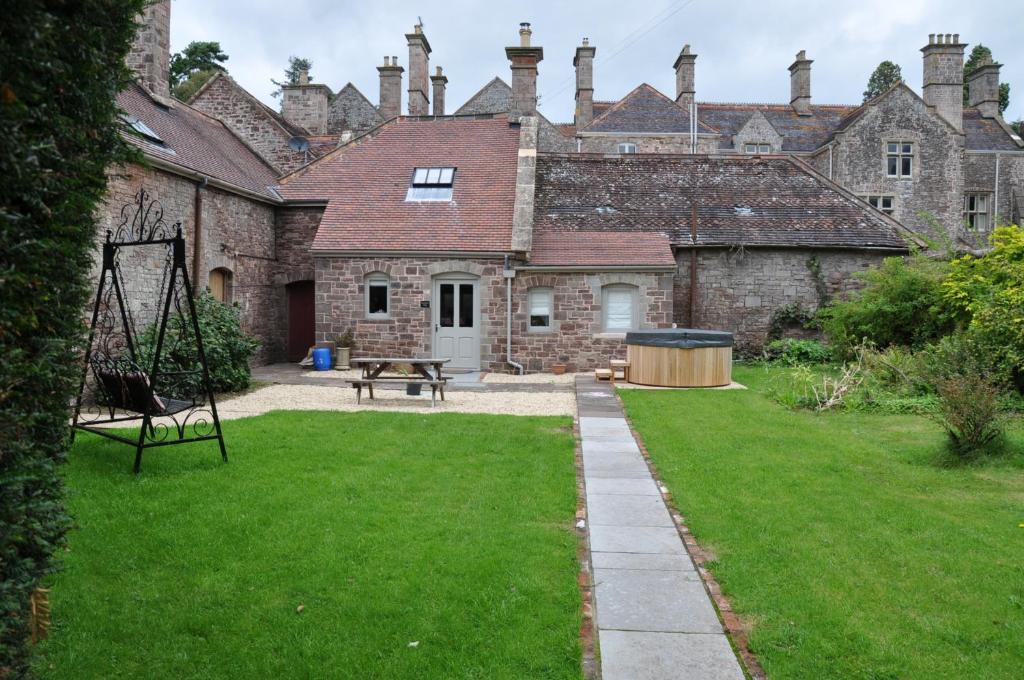阿斯克的住宿－Cecile's Cottage at Cefn Tilla Court, Usk，一座古老的石头建筑,在院子里设有野餐桌