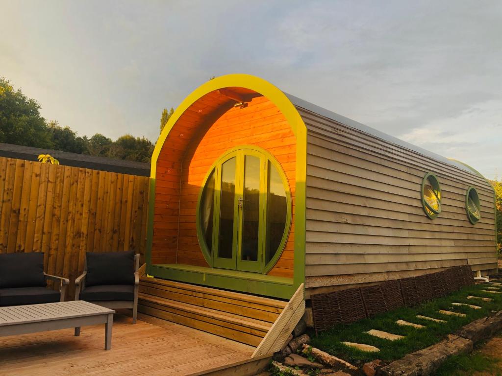a small house with an arched window on a deck at Rural self contained cosy pod house. in Garway