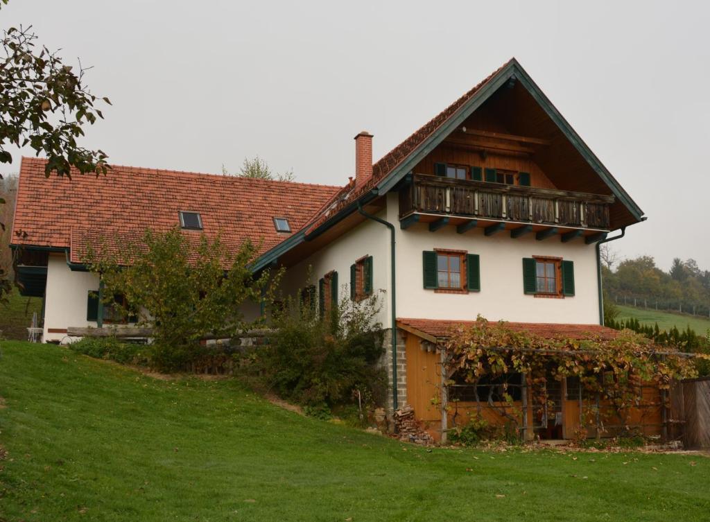 a white house with a balcony on a hill at Bauernhof Grain in Feldbach