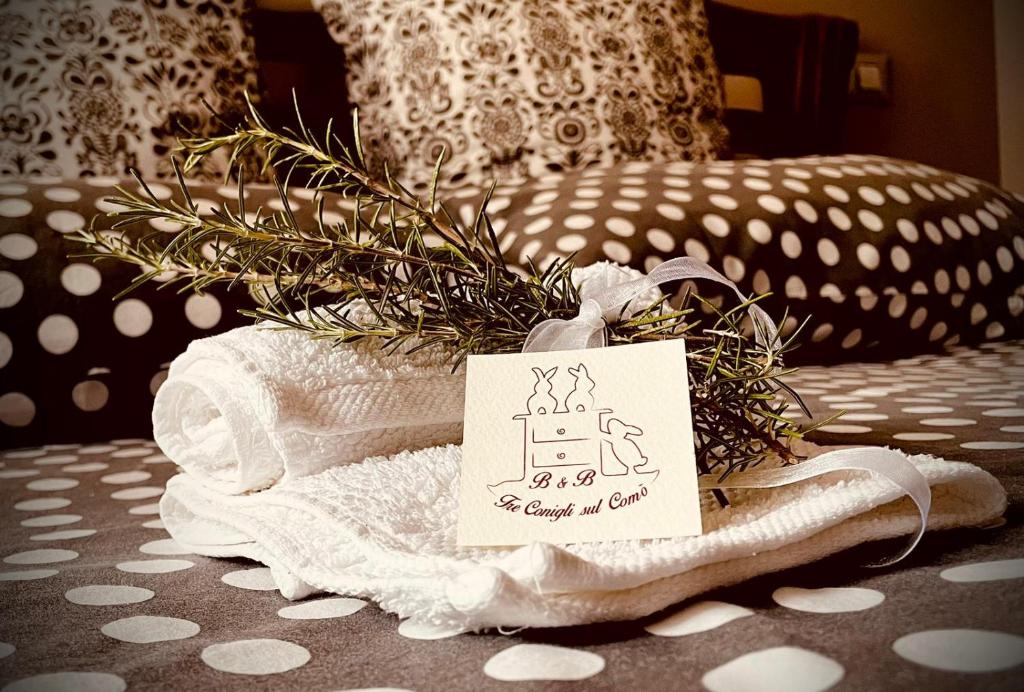 a pile of towels on a bed with a sign on it at B&B Tre Conigli sul Comò in Foligno