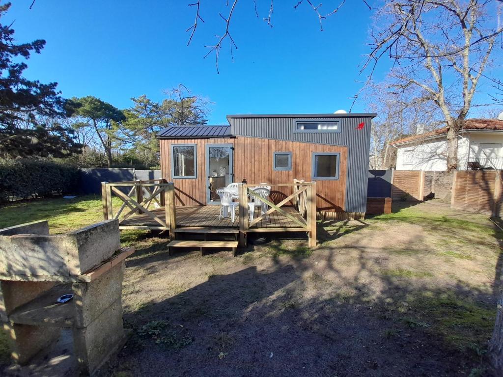 ein winziges Haus mit einer Veranda und einem Zaun in der Unterkunft Maison Tiny House 2 chambres Soulac a 500m plage in Soulac-sur-Mer