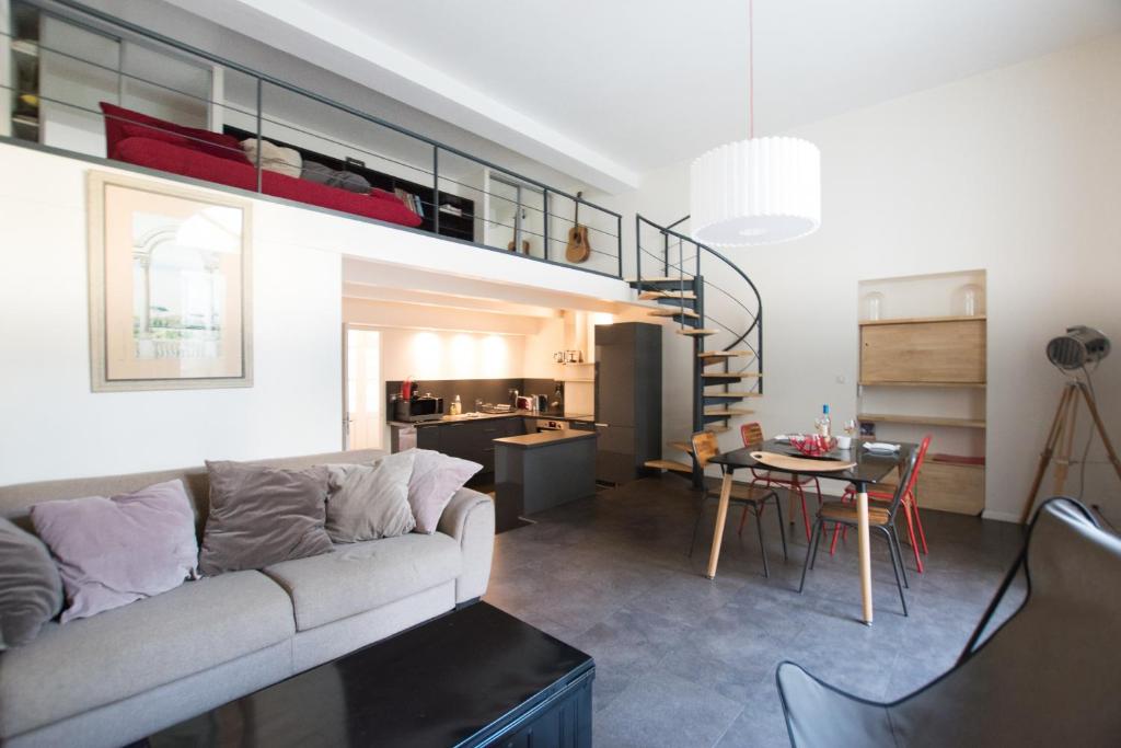 a living room and kitchen with a couch and a table at Divonne - Loft cosy avec jardin partagé in Arles