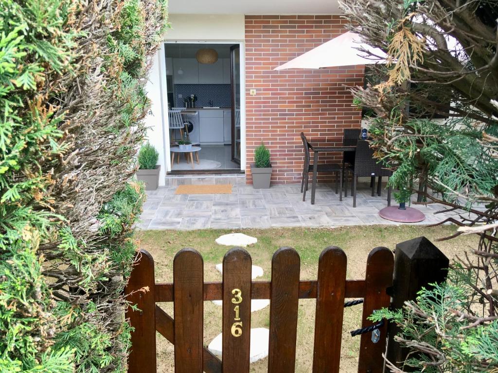 une clôture en bois devant une maison avec une terrasse dans l'établissement Rez de jardin en Accès direct mer(100m) près de la Thalasso, à Cabourg