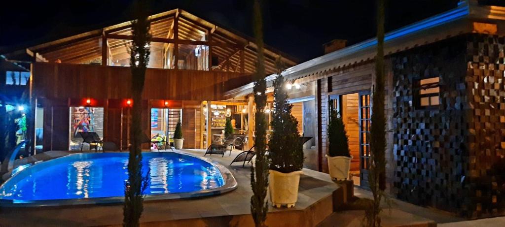 a swimming pool in the middle of a house at night at SPA Rossett em Itapoá - Luxo e conforto c piscina, hidromassagem e cromoterapia, p 22 pessoas! in Itapoa