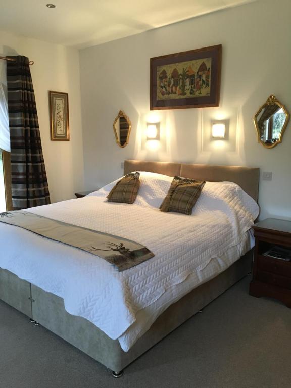 a bedroom with a large white bed with two pillows at Dalmunach House in Aberlour