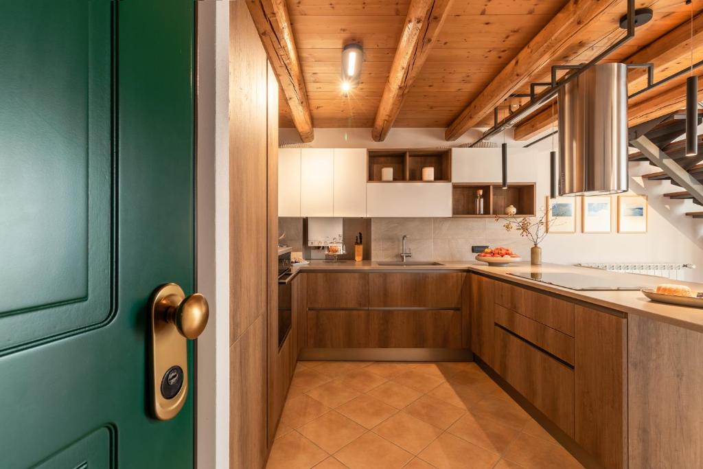 a kitchen with wooden cabinets and a green door at Casa del Borgo "Aria & Acqua" sul Lago Maggiore in Maccagno Inferiore
