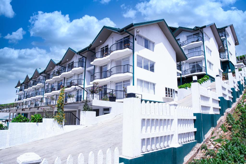 a white apartment building with a white fence at Moon Plains Luxury Apartments in Nuwara Eliya