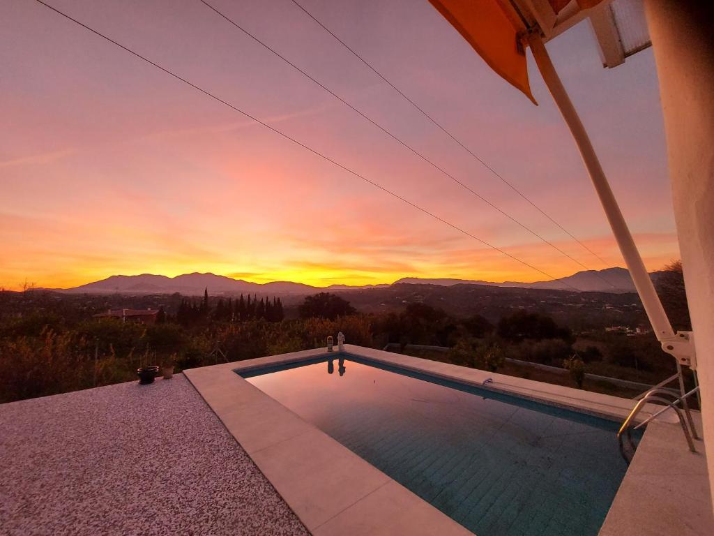 a swimming pool with a sunset in the background at B&B Buena Vista in Alhaurín el Grande