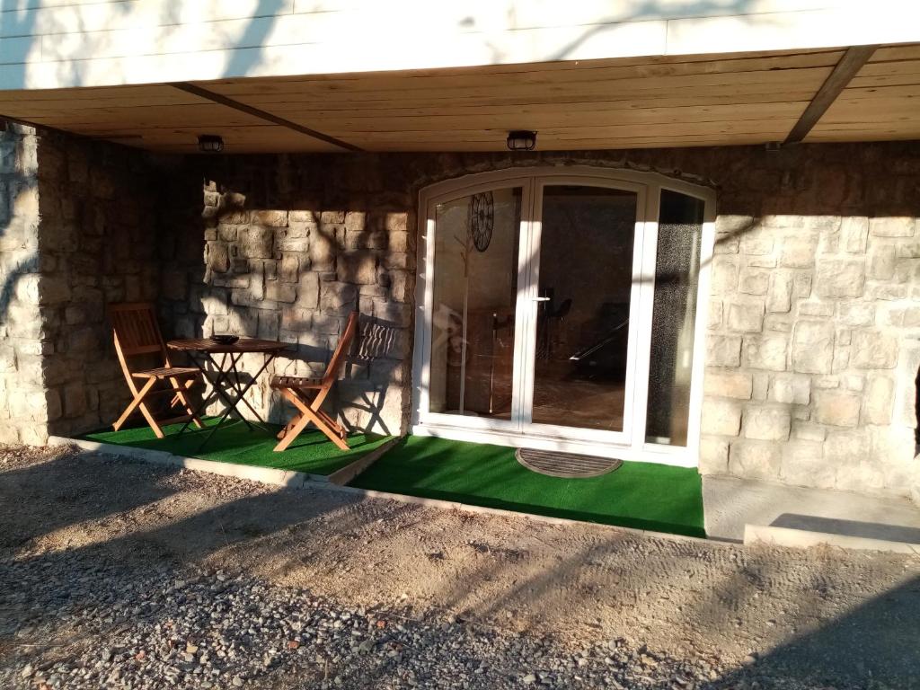 a patio with a table and chairs in front of a building at Studio de Charme neuf à la Montagne in Puget-Rostang