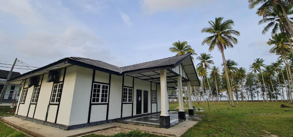 um pequeno edifício com palmeiras num campo em The Saddle Resort em Kuantan