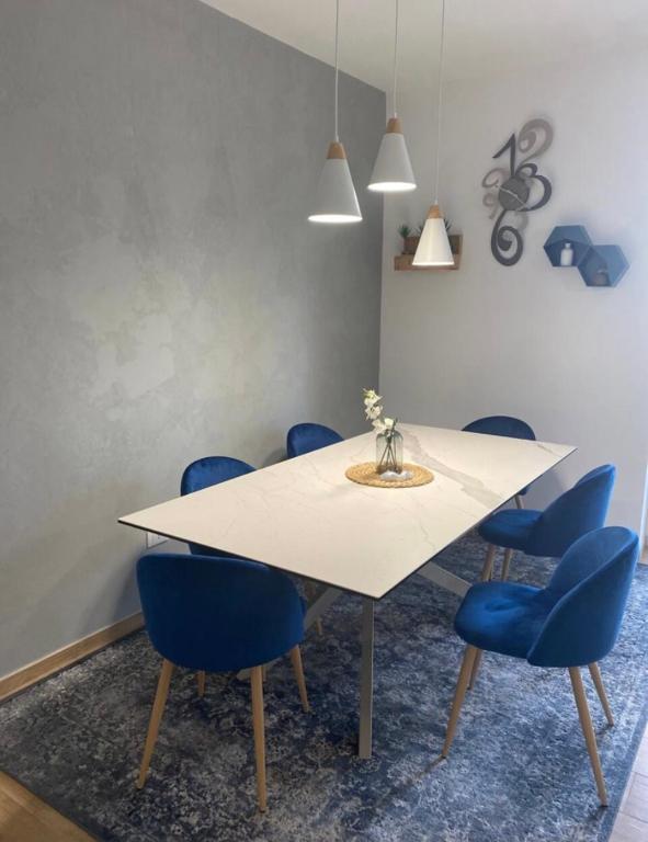 a dining room with a white table and blue chairs at Casa Molly appartamento Guidonia Tivoli terme in Guidonia
