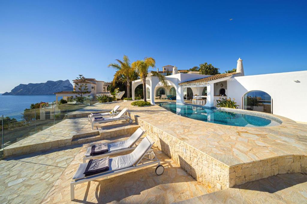 a villa with a swimming pool next to the ocean at VERTIGO- Managed by Almarina in Benissa