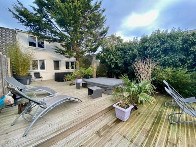 een achtertuin met een houten terras met stoelen en een bank bij L'Etoile Filante et Constellations in Wimereux