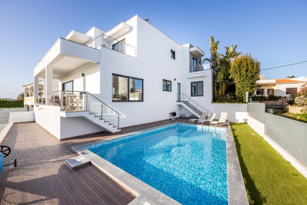 a villa with a swimming pool in front of a house at Villa Celestine in Portimão