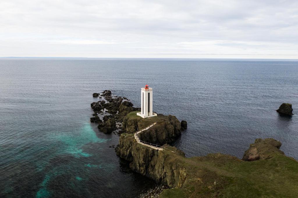 un faro en una isla rocosa en el océano en NorthEast Guesthouse, en Bakkafjörður