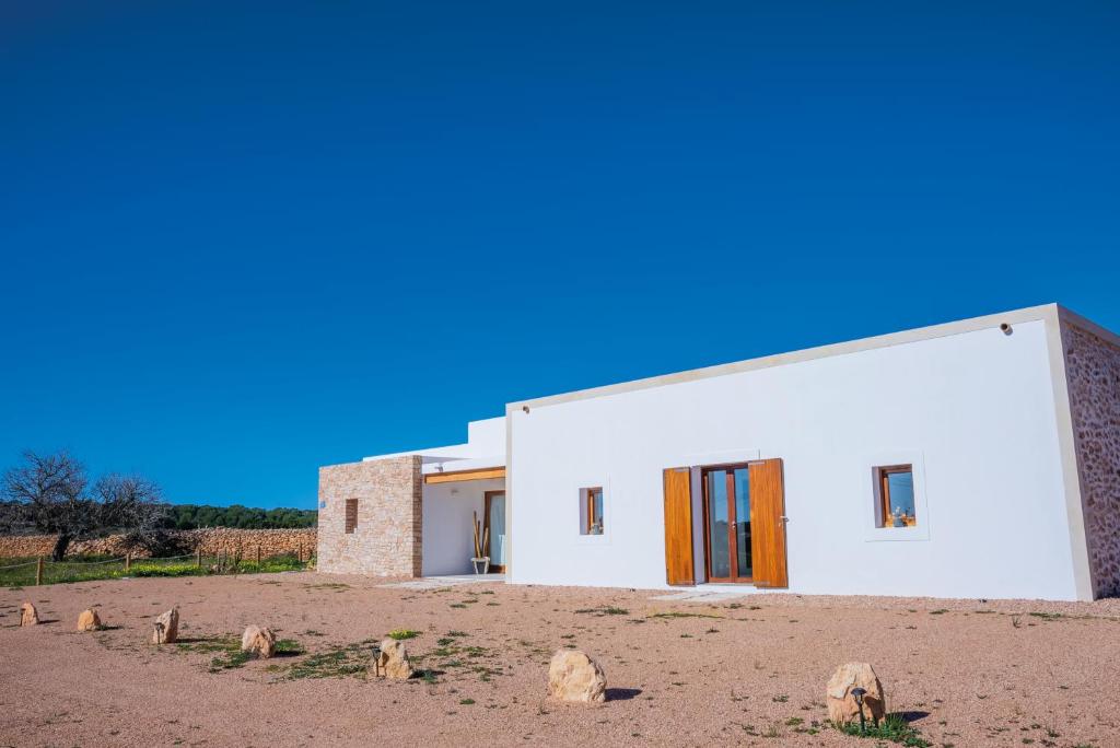 a white building with orange doors in a field at NEW LUXURY VILLA - Es Pujol de na Rita in La Mola