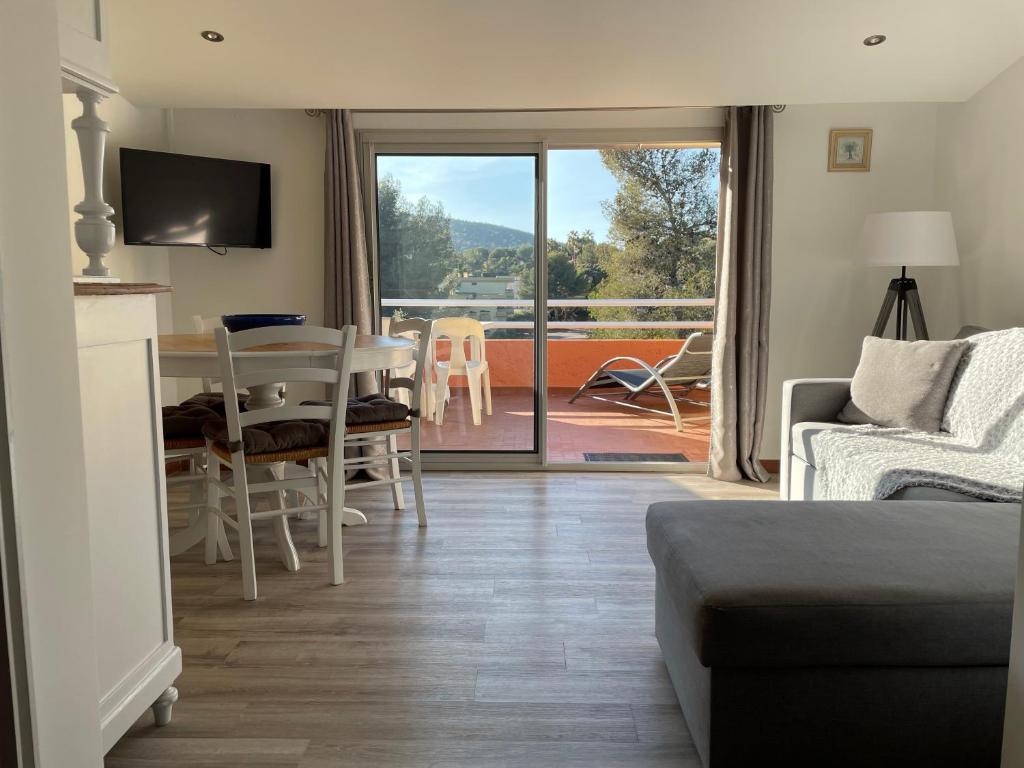 ein Wohnzimmer mit einem Sofa und einem Tisch sowie einem Balkon in der Unterkunft Appartement Bord de Mer La Faviere in Bormes-les-Mimosas