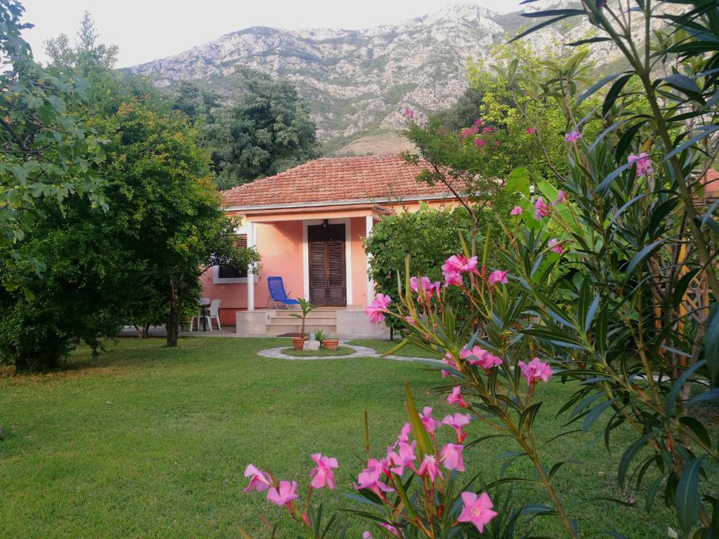 une petite maison avec des fleurs roses dans la cour dans l'établissement Holiday home Neimarevic, à Risan