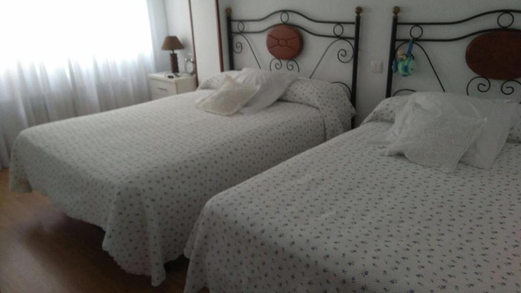 2 camas en una habitación de hotel con sábanas blancas en Apartamento Gijon Playa, en Gijón
