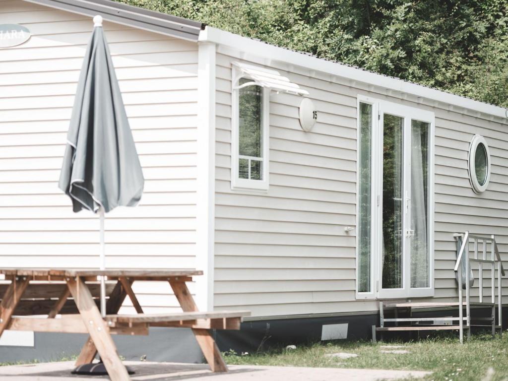 an umbrella and a picnic table in front of a house at Fine chalet with microwave located in the Ardennes in Olloy-sur-Viroin