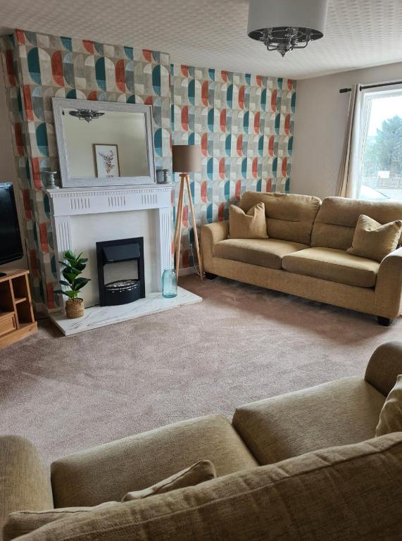 a living room with two couches and a fireplace at North Coast Property - Number 15 in Thurso