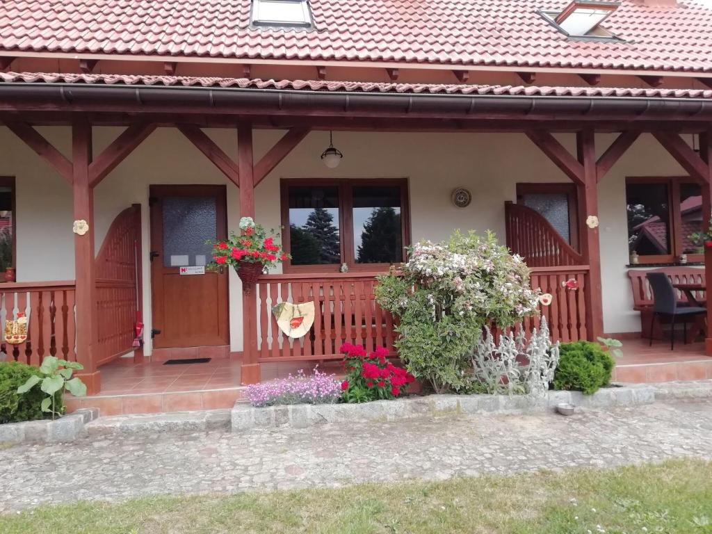 a house with a porch with flowers on it at Holiday homes under the willow tree, Kolczewo in Kołczewo